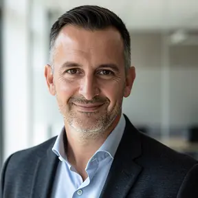 Professional headshot of a French man in his mid 40s, modern business casual look, natural light, neutral office background slightly blurred, confident and approachable expression, realistic photography, high resolution
